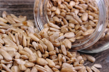 Sunflower seeds spilling out of glass jar. Wooden background