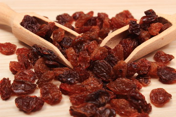 Brown raisins with spoon on wooden table, healthy eating
