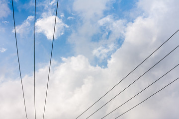 Fototapeta premium Power transmission lines - Power transmission lines run across a blue sky being covered with fast approaching grey rain clouds.