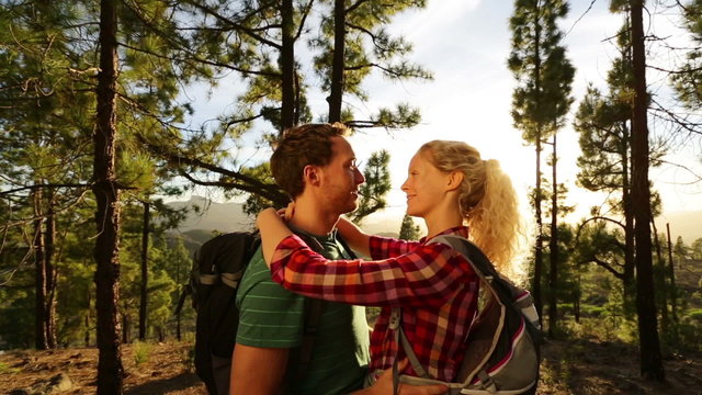 Kissing couple at sunset hiking in forest. Romantic hikers embracing in love enjoying view and romance at sunset in beautiful mountain landscape, on Gran Canaria, Canary Islands, Spain.