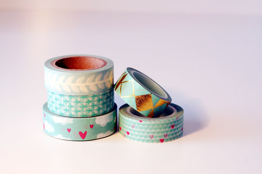 Piccola pila di rotoli di nastro adesivo washi tape. Tonalit&agrave; verde e azzurro. Sfondo bianco