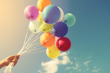 Girl hand holding multicolor balloons done with a retro instagram filter effect, concept of happy...