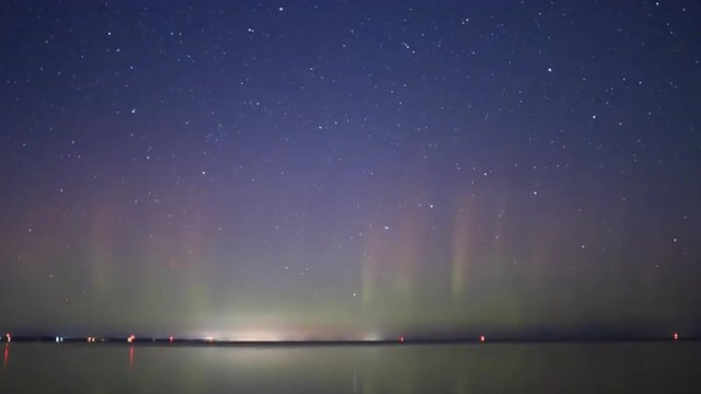 Red and green aurora borealis light pillars in starry night sky, Taurid meteorite fireball descending over Lake Simcoe. 4k time lapse