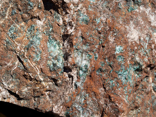 Cooper inclusions on the red surface of stone.