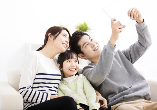  Happy young family taking selfies on sofa