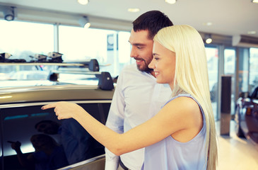 happy couple buying car in auto show or salon