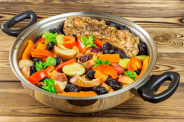 Healthy food, stewed pork meat with various colorful vegetables in pan on wooden background