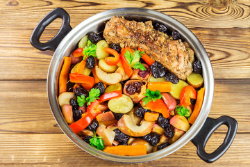 Healthy food, stewed pork meat with various colorful vegetables in pan on wooden background, top view