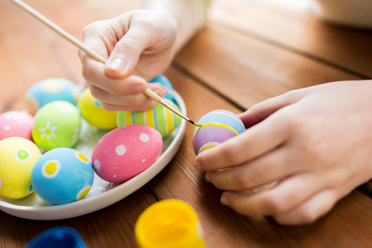 Naklejki close up of woman hands coloring easter eggs