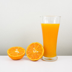 The glass of tasty pure orange juice and fresh orange half for a good healthy.