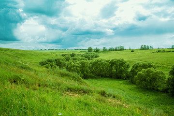 Green fields and hills under the cloudy sky.