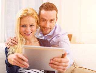 Young attractive couple having fun using tablet