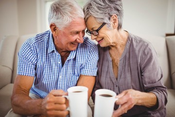 Senior couple having coffee in living room