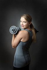 sporty woman on grey background with dumbbells
