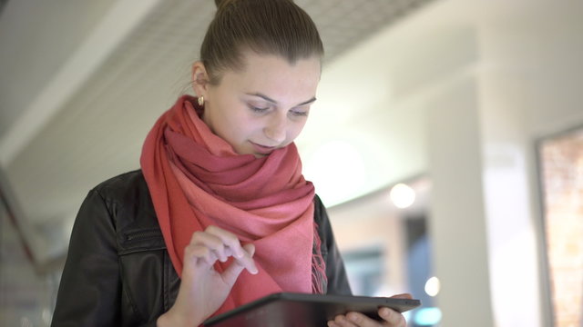 Blonde using tablet, smiling wearing. Urban female professional in her 20s. 4K