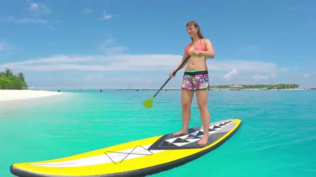 Young woman stand up paddling in exotic island resort