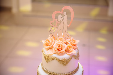 big white wedding cake with the roses on a white table