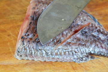 fresh water fish and knife prepare for cook on wooden chop block