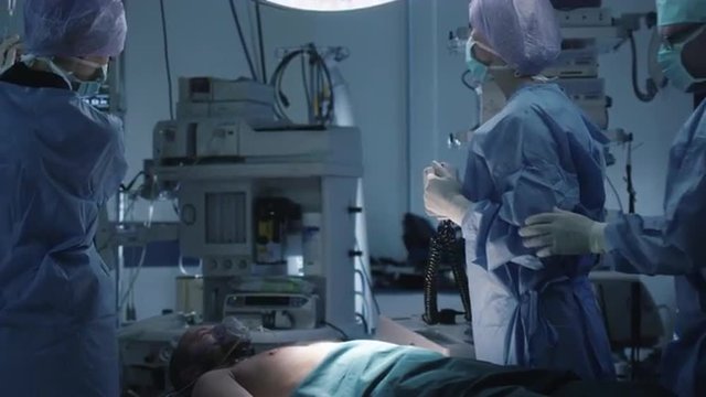 Medical Team Performing Defibrillation in Modern Operating Room. Shot on RED Cinema Camera.