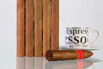 Different cigars and cup of coffee on a  glass table