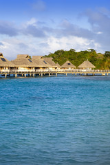 island with palm trees and small houses on water in the ocean