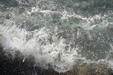 Fototapeta na wymiar Wave on the pebble coast of sea