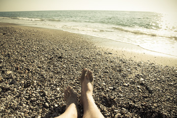 Male legs on the pebble coast of sea. Selective focus. Toned