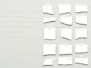 Close-up of multiple pieces of paper on white brick wall background