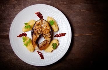 Fried tuna fish with mashed potato, dried tomato and parsley on