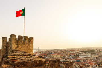 Portuguese flag on top of Castle Sao Jorge in Lisbon, Portugal, looking over the city at sunset