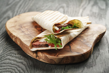 fresh homemade burritos with beef on olive cutting board