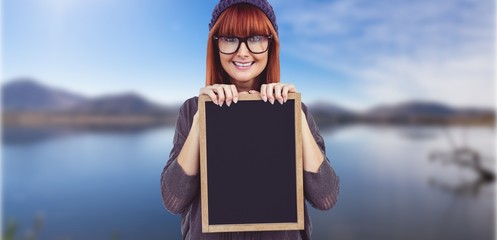 Composite image of smiling hipster woman holding blackboard