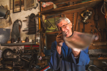 Senior tinsmith in his workshop. - obrazy, fototapety, plakaty