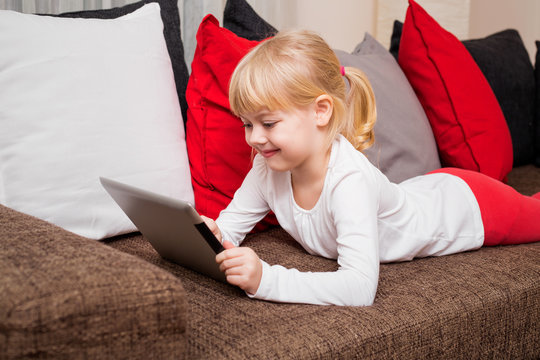 Child lying on the couch and using tablet 