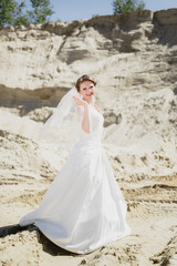 Fototapeta na wymiar blonde bride on a sand in white dress