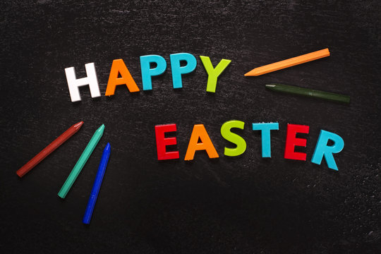 Happy easter greeting card with bright letters and pencils. Toned image. Top view