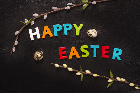 Happy easter greeting card with bright letters, willow branches and quail eggs. Toned image. Top view