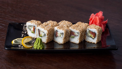 close up of sushi roll on a plate with ginger and lemon