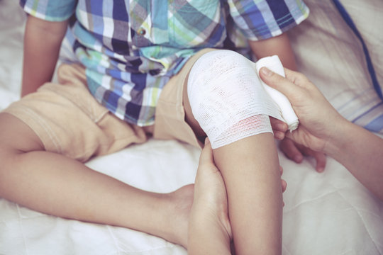 Child injured. Mother bandaging son's knee. Vintage style.