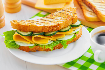 Sandwich with cheese, lettuce and vegetables for breakfast with coffee