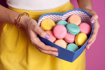 Girl holding colorful French macarons in hands