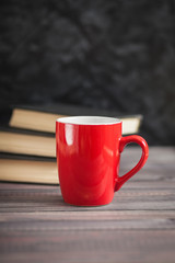 The red cup and black books on a dark background