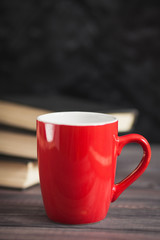 The red cup and black books on a dark background