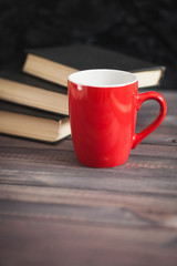 The red cup and black books on a dark background