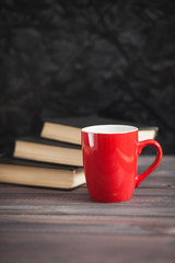 The red cup and black books on a dark background