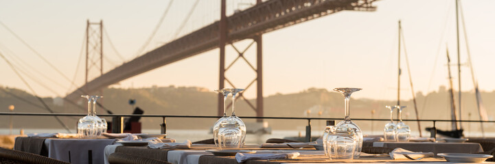 The 25th of April Bridge in Lisbon, in front a resturant table waiting for costumers.