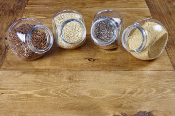 Leinsamen, Quinoa, Chia, Amaranth in Gläsern auf Holztisch