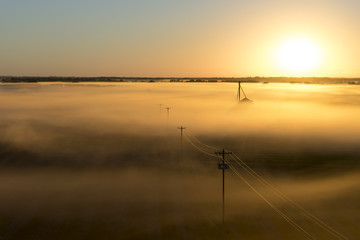 Telephone poles and farm ranch rural countryside silo on a foggy misty morning at sunrise or sunset