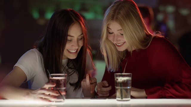 Junge Frauen sto&szlig;en mit Longdrink an
