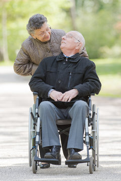 Wife pushing elderly husband in wheelchair